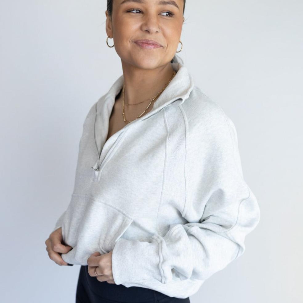 Casual portrait of a woman wearing a light gray Cozy Up Full Length 1/2 Zip Sweatshirt by DYM Athletics, showcasing comfort and chic design.