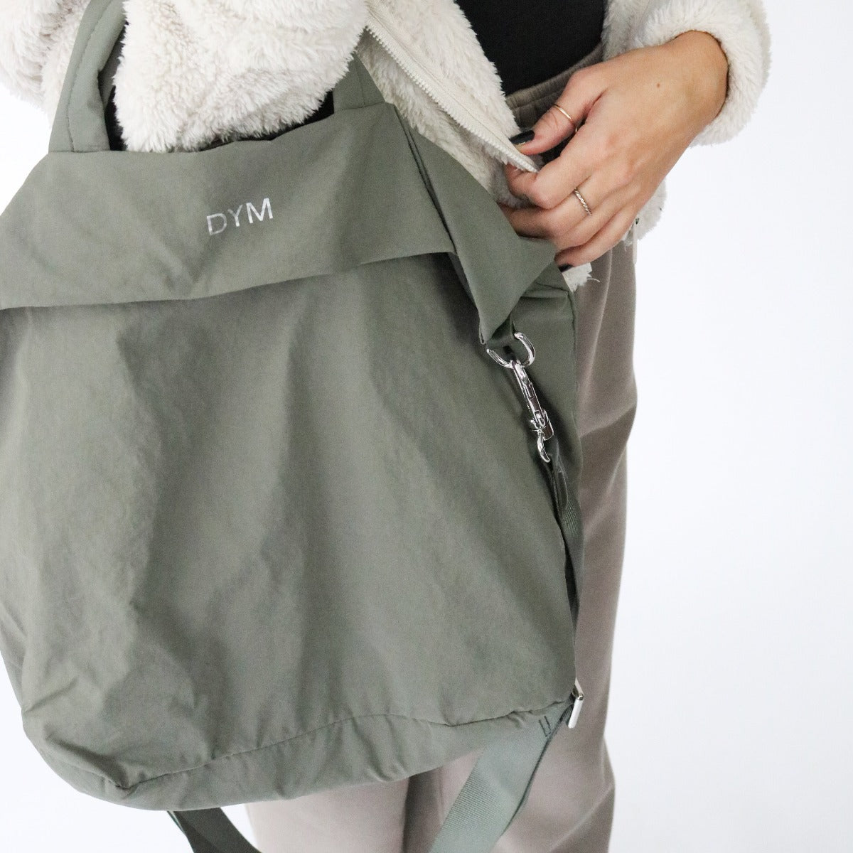 DYM Athletics In Motion Bag in olive green, worn casually by a person, highlighting its versatility and modern aesthetic.