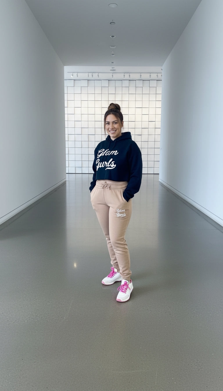 Model in a Customized Glam Gurls Cropped Hoodie with Puff Print, sporting beige joggers and a relaxed look in a modern interior. This stylish hoodie is available in sizes S-XL from Glam Gurls.