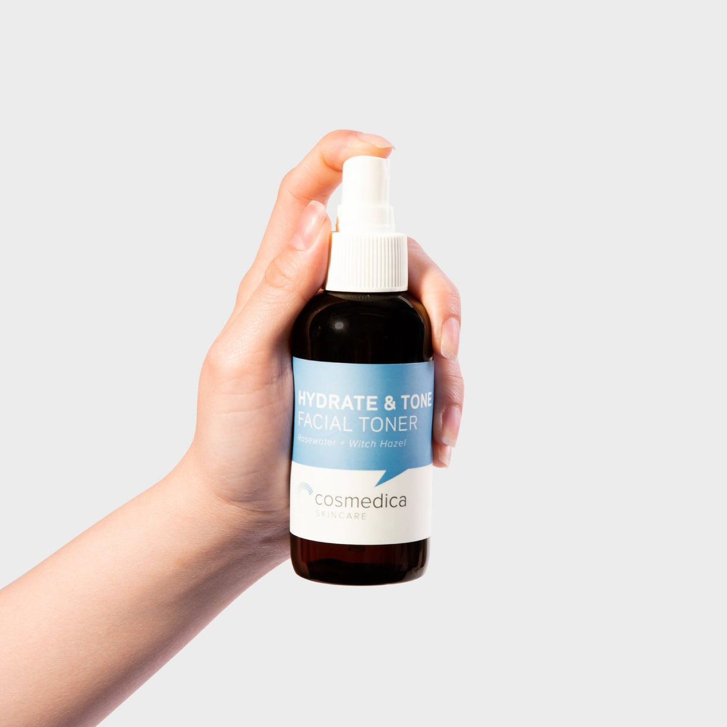Hydrate & Tone Rosewater Witch Hazel Face Toner by Cosmedica Skincare being held in a hand, showcasing its convenient size and packaging.