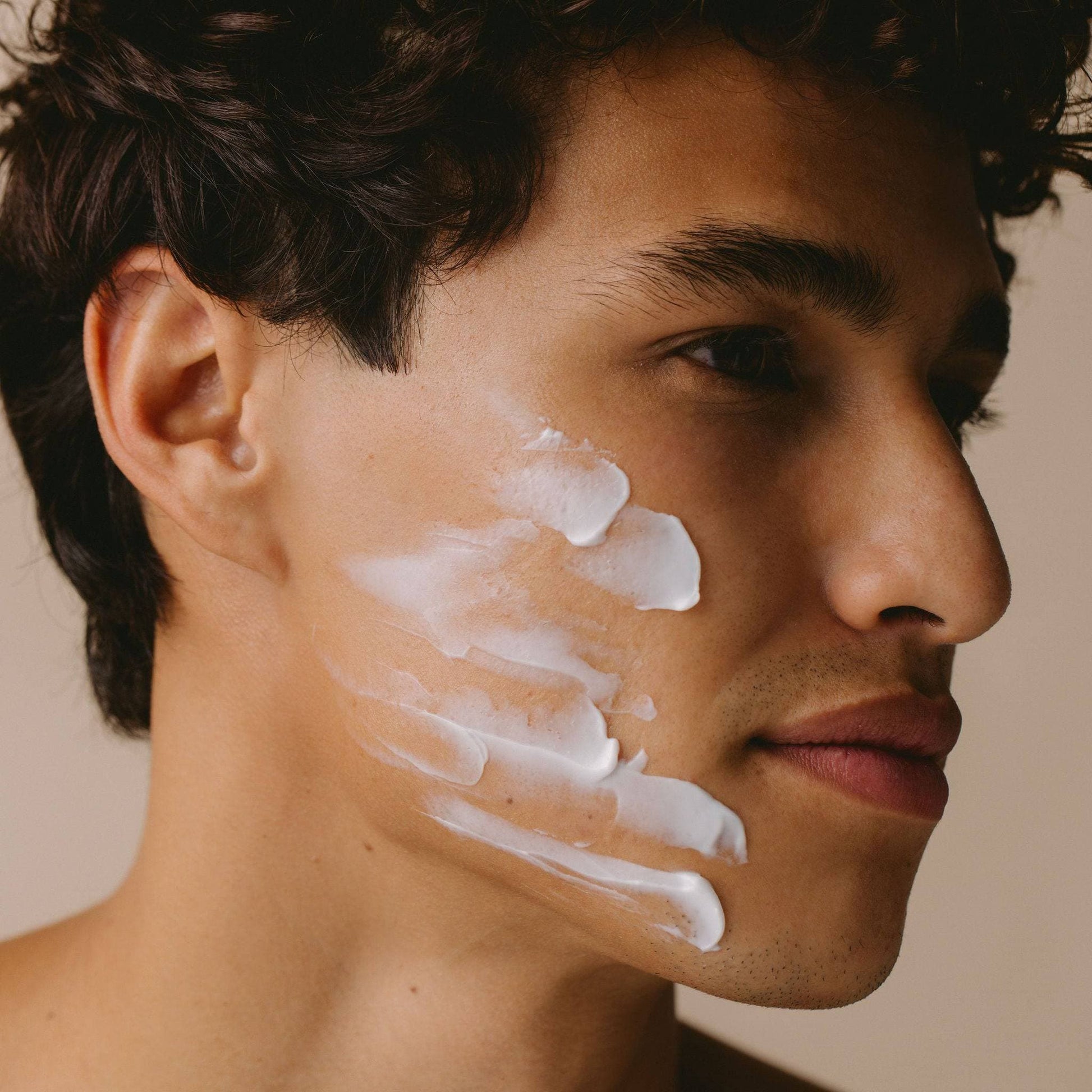 Man applying skincare products from Cosmedica Skincare's Complete Complexion Kit on his face, demonstrating the 2.5% Glycolic Facial Scrub.