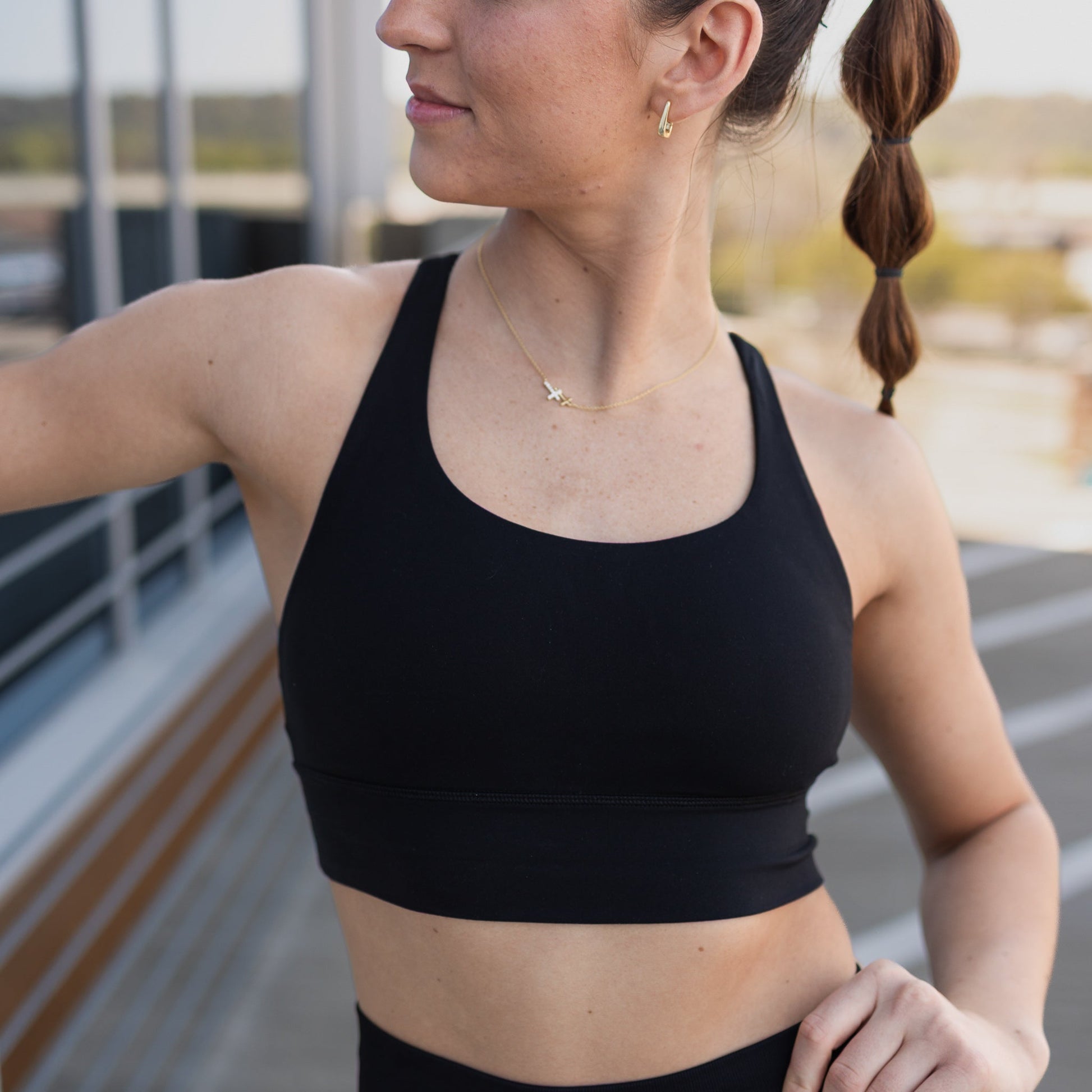 Woman showcasing the Zone Bra by DYM Athletics in black, highlighting its comfort and style for high-impact workouts.