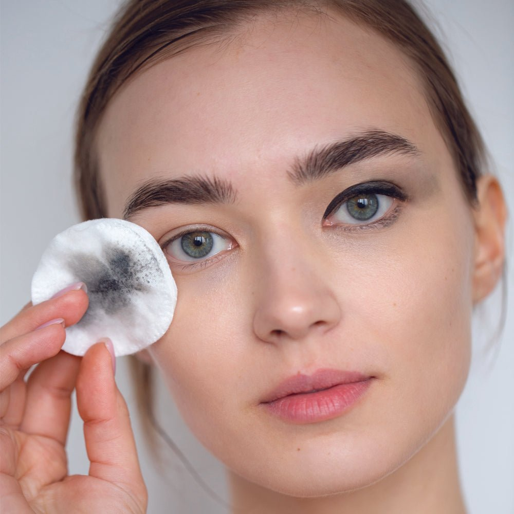 Model using cotton pad to remove makeup with Glimmer Goddess Organic Cucumber Makeup Remover, highlighting its effectiveness, by GNS Beauty & Personal Care.