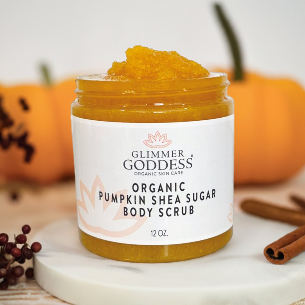 Glimmer Goddess Organic Pumpkin Shea Sugar Body Scrub displayed with pumpkins and cinnamon, ideal for a cozy, fall skincare routine.