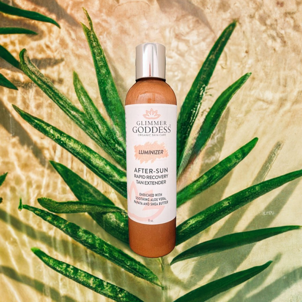 Glimmer Goddess Organic After Sun Lotion bottle surrounded by tropical leaves, showcasing the Tan Extender & Luminizing Shimmer by GNS Beauty & Personal Care.