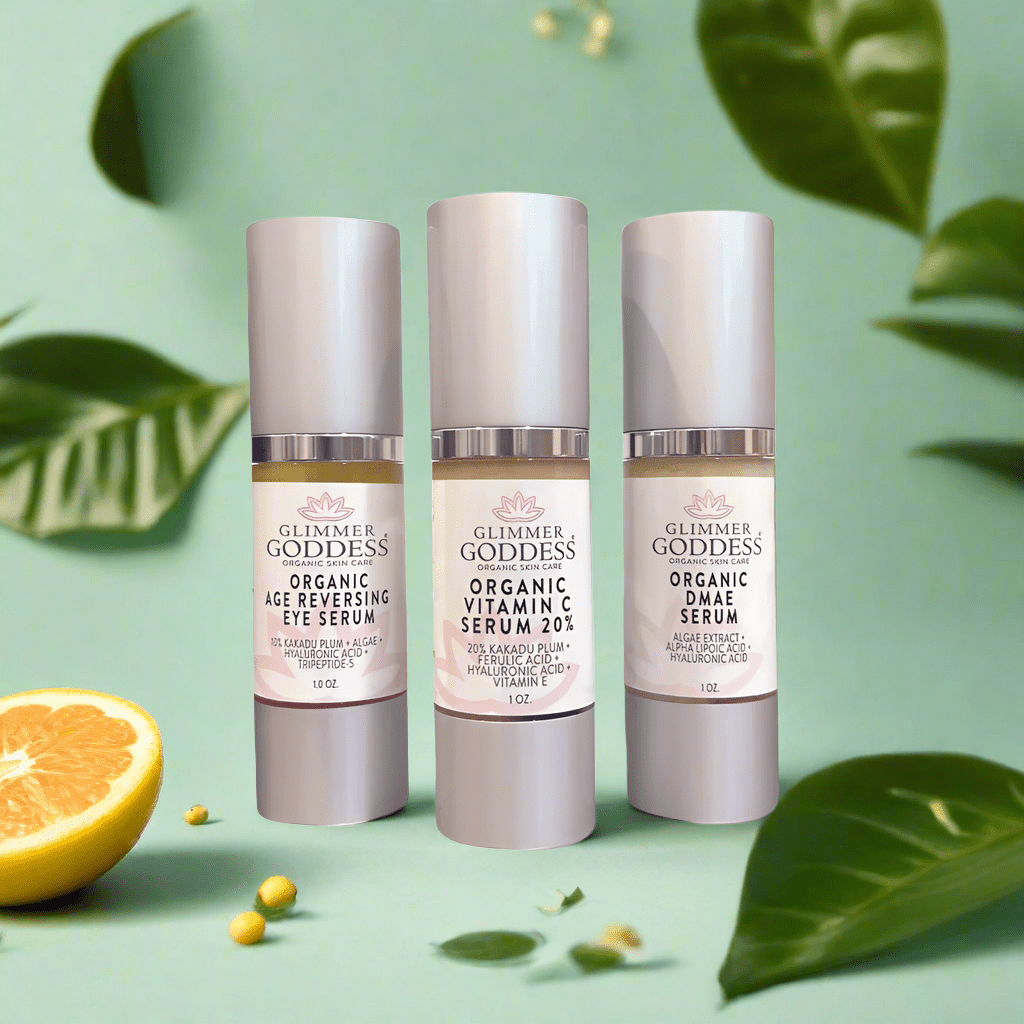 Glimmer Goddess Organic Anti-Aging Trio displayed with vibrant lemons and green leaves, showcasing the Age Reversing Eye Serum, Vitamin C Serum 20%, and DMAE for radiant skin.