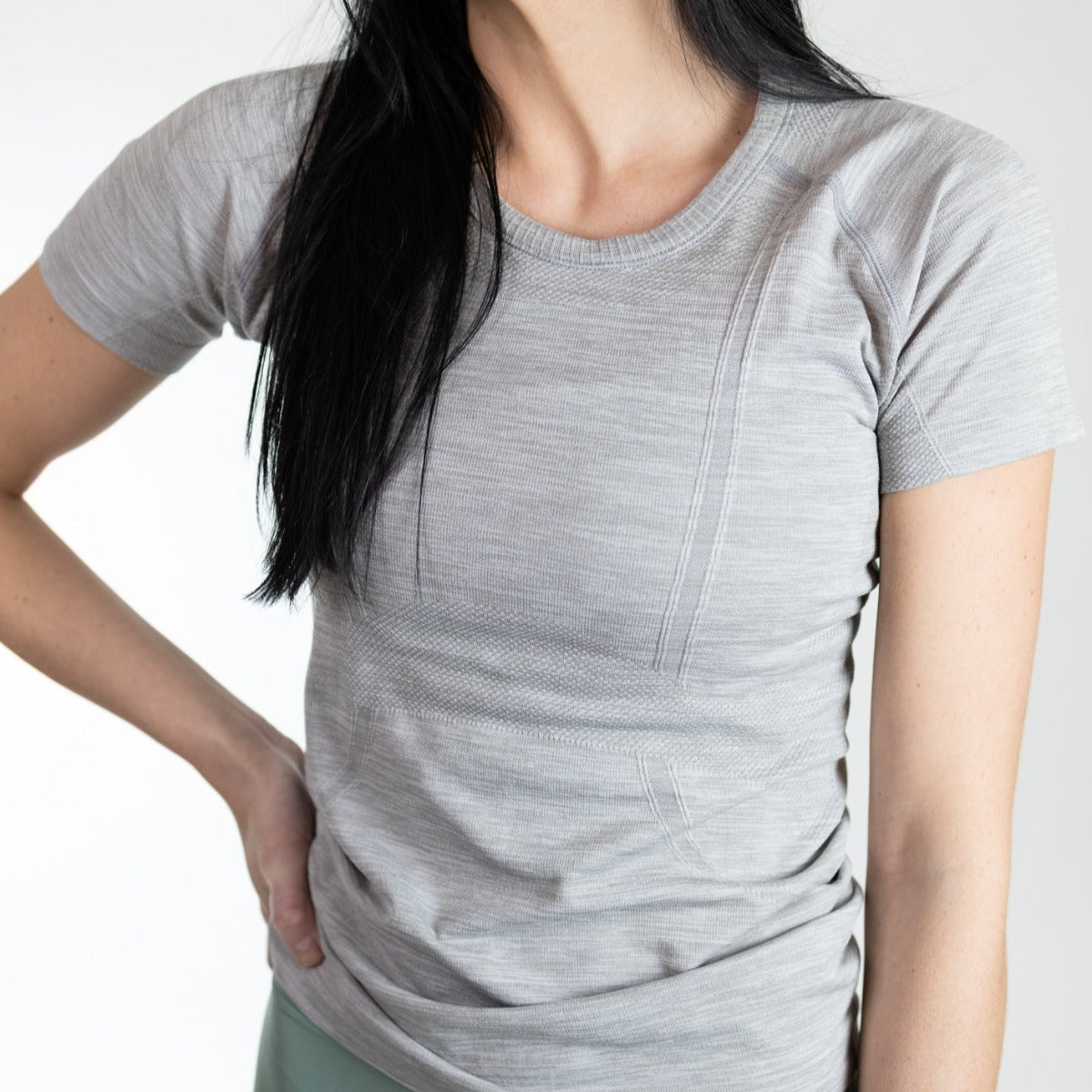 Female model wearing a light gray Trainer Lightweight Short Sleeve Shirt by DYM Athletics, demonstrating its stylish and functional design.