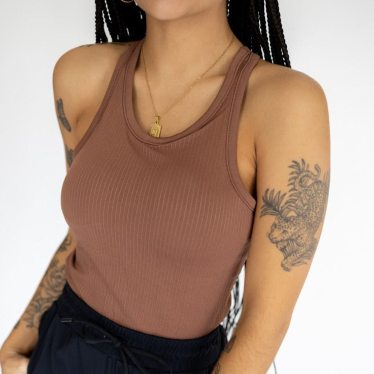 Close-up of a model wearing the Restore Ribbed Comfort Tank with Built-in Bra by DYM Athletics in a warm brown shade, featuring a sleek ribbed texture and stylish silhouette.