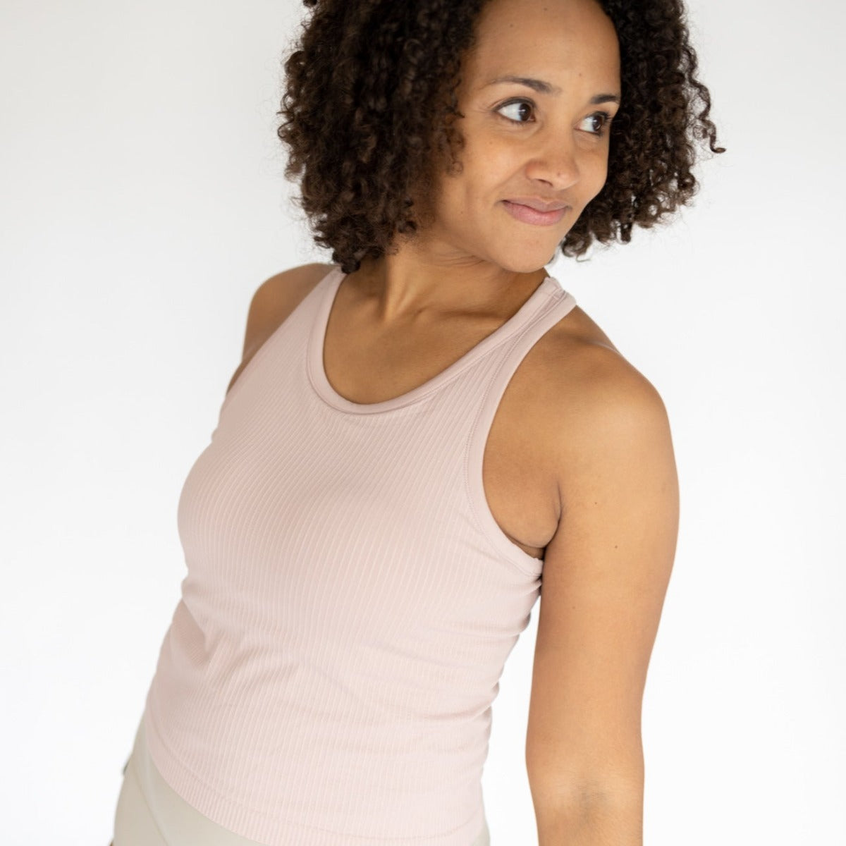 Model showcasing the soft pink Restore Ribbed Comfort Tank with Built-in Bra by DYM Athletics, highlighting its comfortable fit and stylish look.