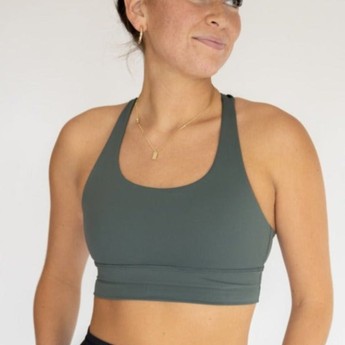 Woman modeling the Zone Bra by DYM Athletics in a stylish green color, perfect for high support during workouts.