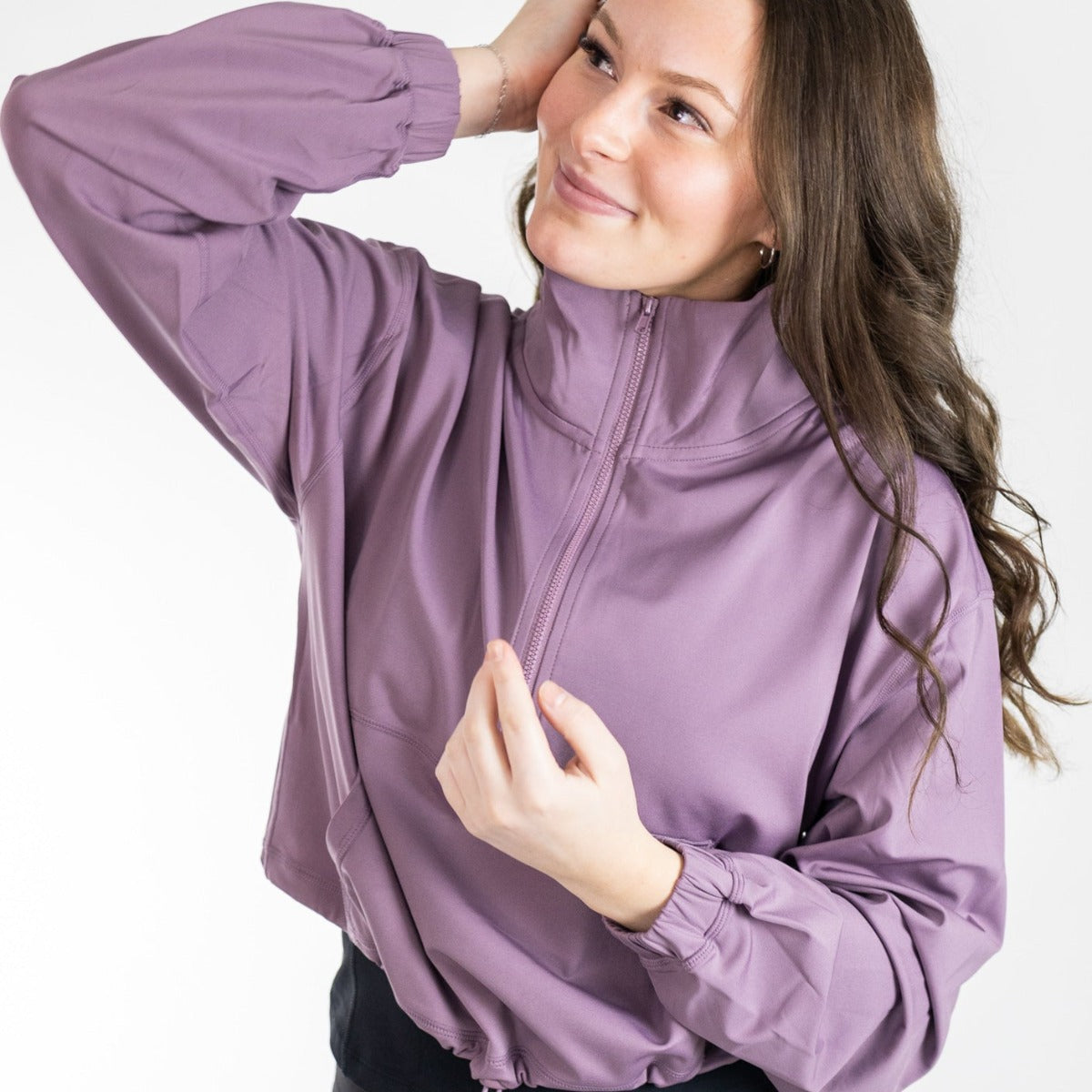 Woman wearing the Ascend 1/4 Zip Jacket by DYM Athletics in a stylish lavender color, showcasing a modern fit and relaxed vibe.