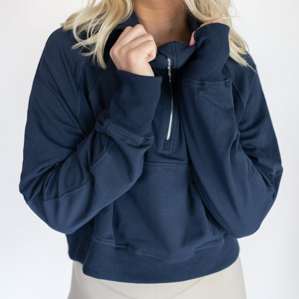 Close-up of a model holding the hood of a navy Lightweight 1/4 Zip Hoodie from DYM Athletics, ideal for stylish workouts or casual outings.