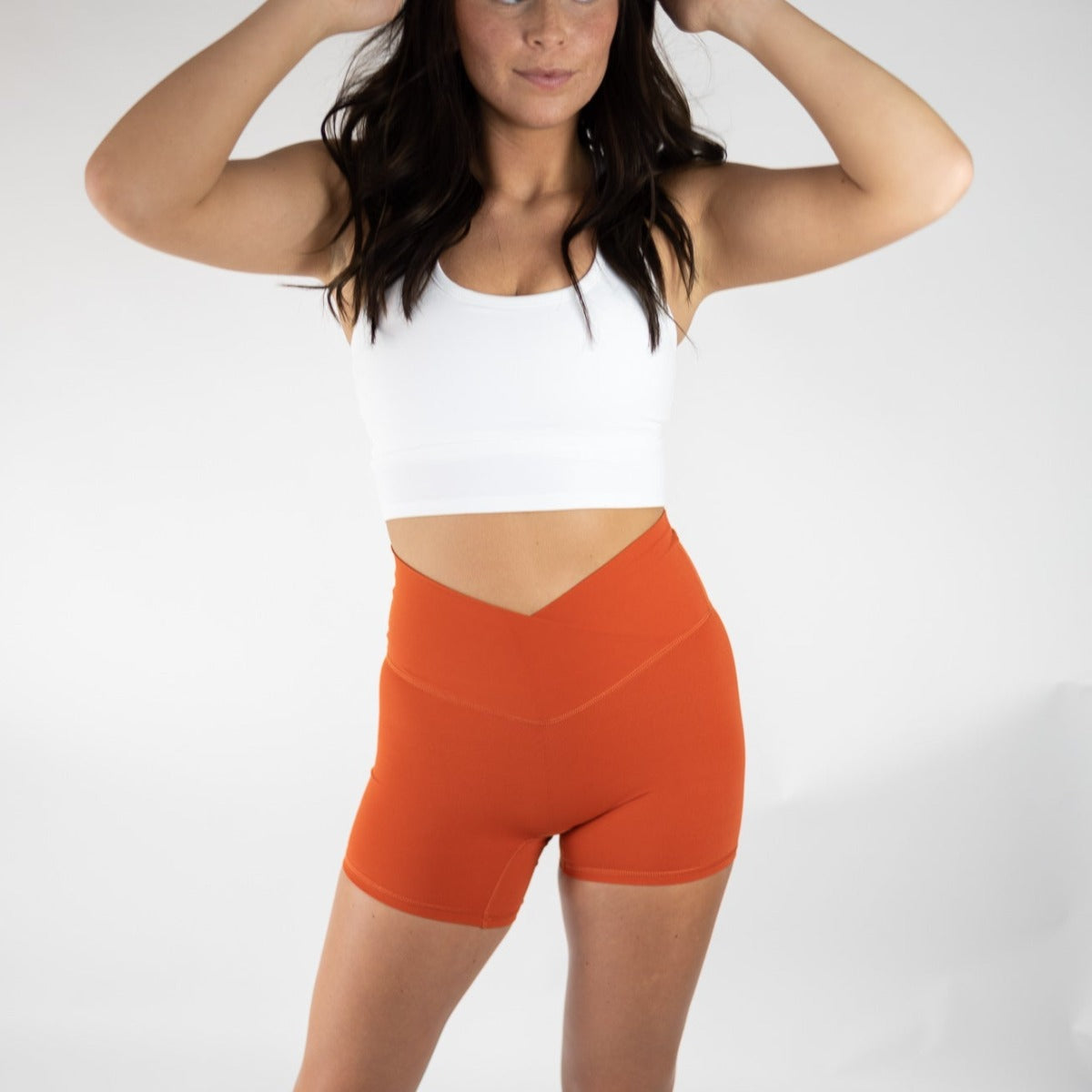Model showcasing DYM Athletics Flex & Flow 4" V-Waist Shorts in orange, designed for comfort and style with light compression, ideal for active lifestyles.