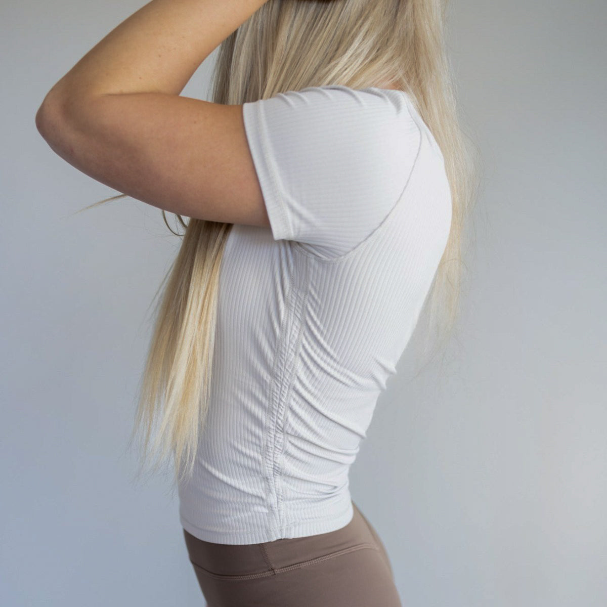 Side view of a model in the Restore Ribbed T-shirt from DYM Athletics, highlighting its snug fit and ribbed texture.