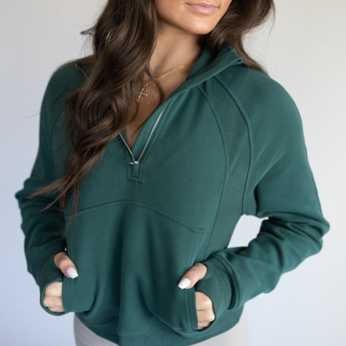 Woman wearing a dark green Cozy Up Full Length 1/2 Zip Sweatshirt by DYM Athletics, showcasing the adjustable zip and pockets, perfect for casual wear.