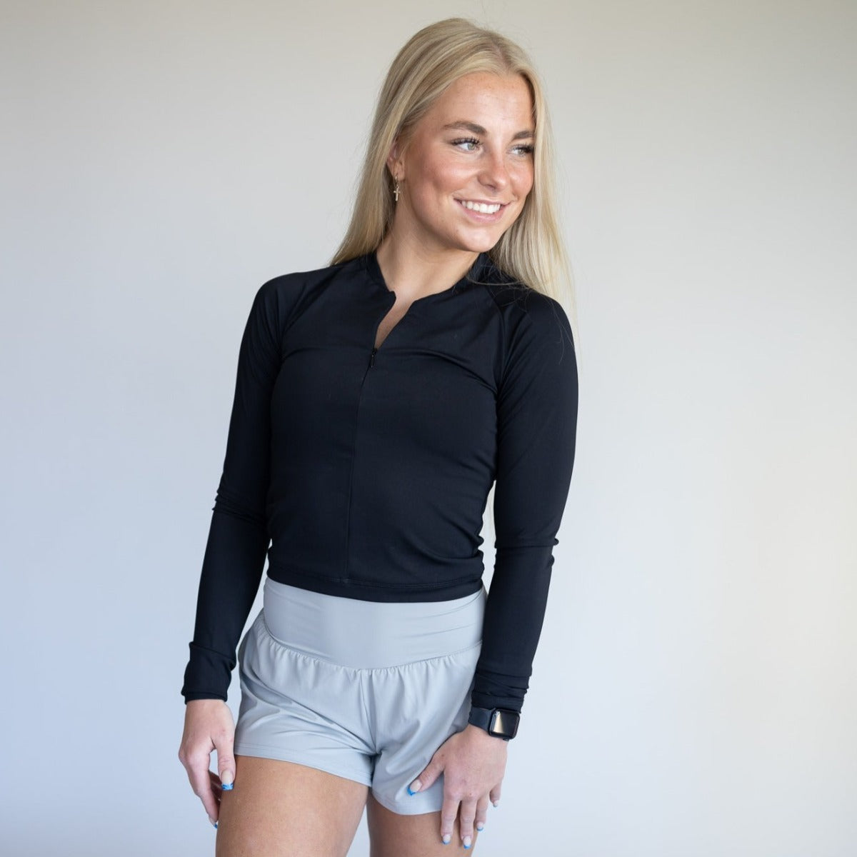 DYM Athletics Elite 1/4 Zip Long Sleeve athletic shirt in black, featuring a fitted design and styled with light gray shorts, perfect for workouts and casual wear.