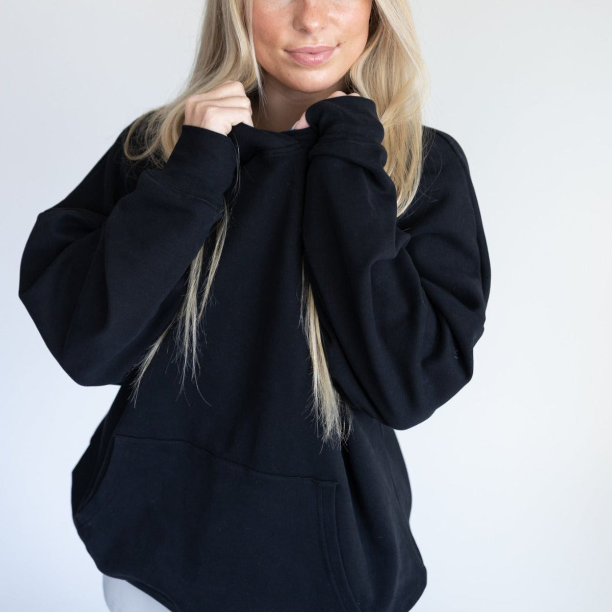 Close-up of a model wearing the Cozy Up Boyfriend Hoodie in black from DYM Athletics, emphasizing the cozy fabric and relaxed hood.