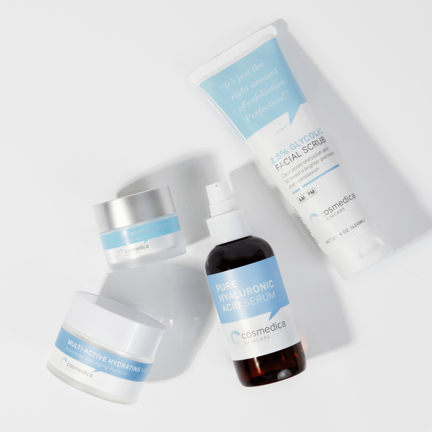 Flat lay of Cosmedica Skincare's Complete Complexion Kit including Pure Hyaluronic Acid Serum, Multiactive Hydrating Night Cream, and 2.5% Glycolic Facial Scrub.