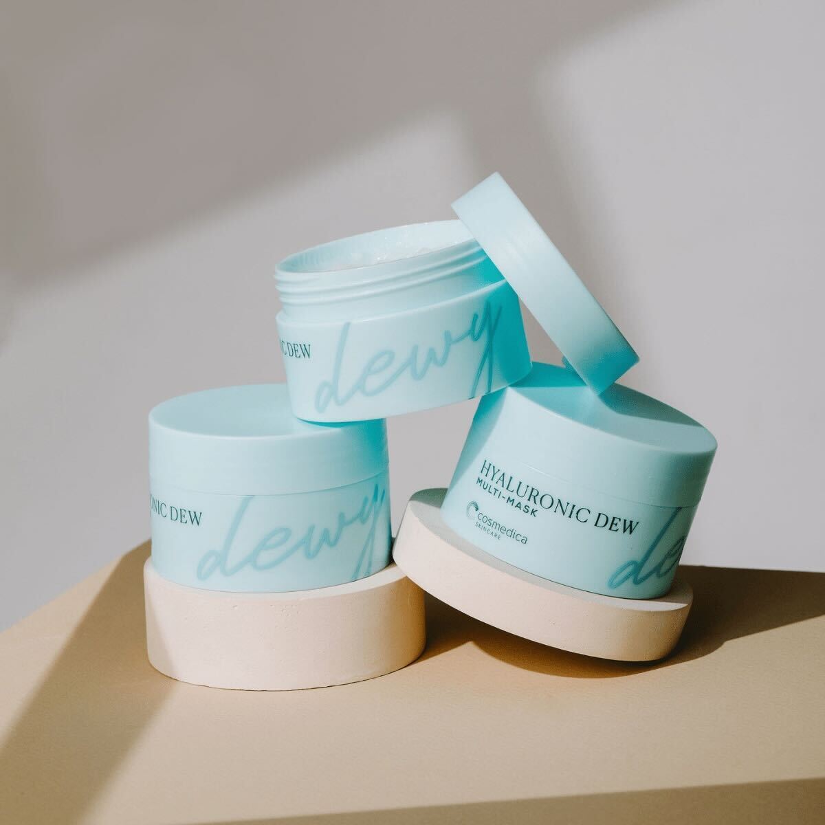 Multiple containers of Hyaluronic Dew Multi-Mask from Cosmedica Skincare stacked together, showcasing the product's stylish packaging.