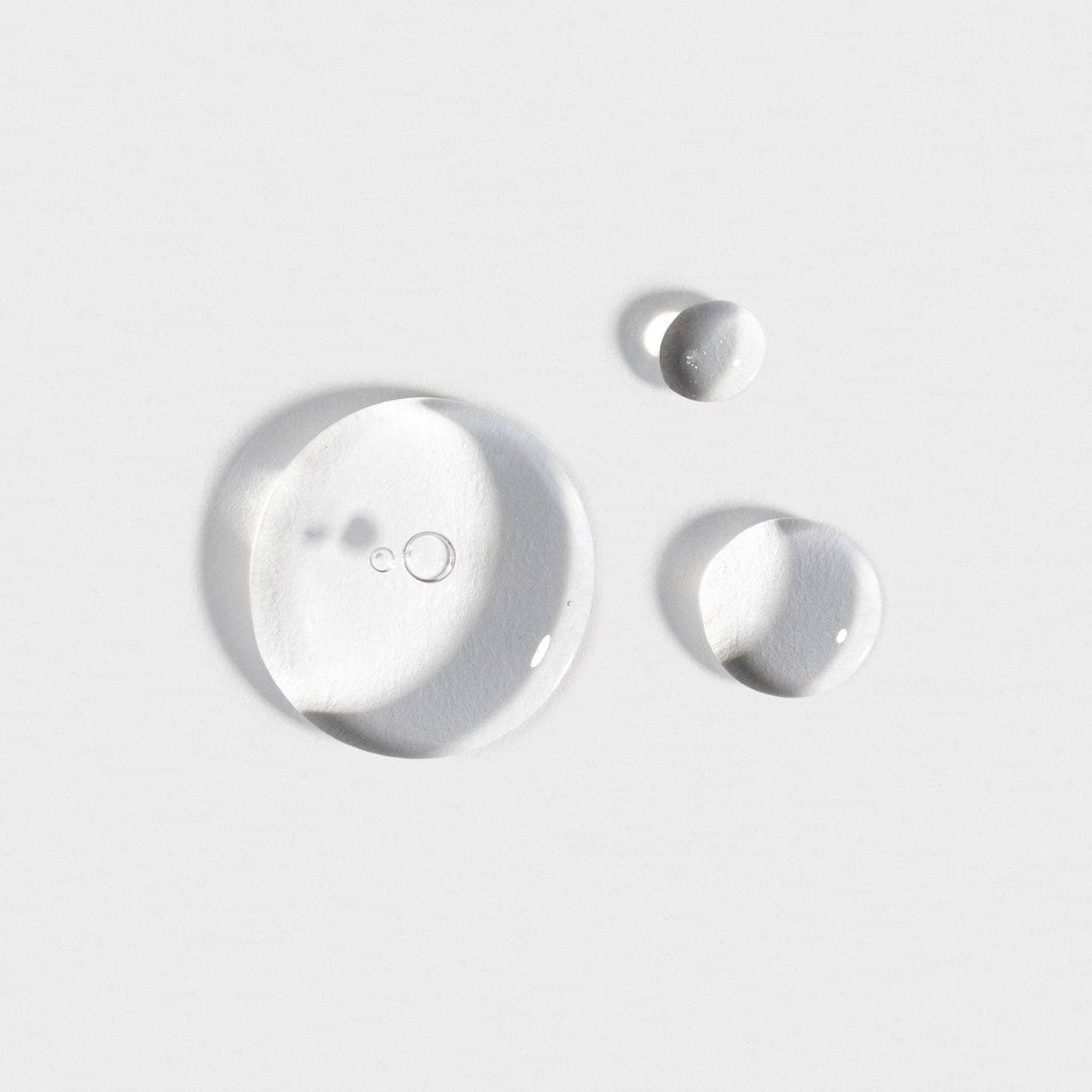 Close-up image of clear serum drops, showcasing the texture and consistency of the products in the Hyaluronic + Vitamin C Serum Set by Cosmedica Skincare.