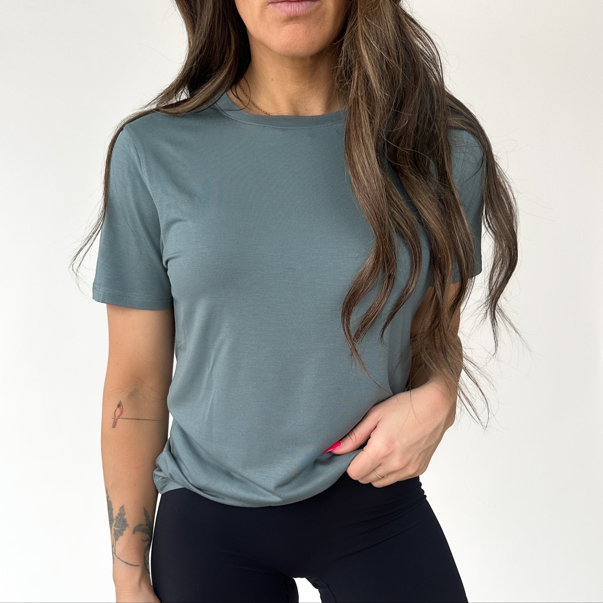 Woman wearing a teal Breathe Bamboo T-Shirt from DYM Athletics, showcasing comfort and style.