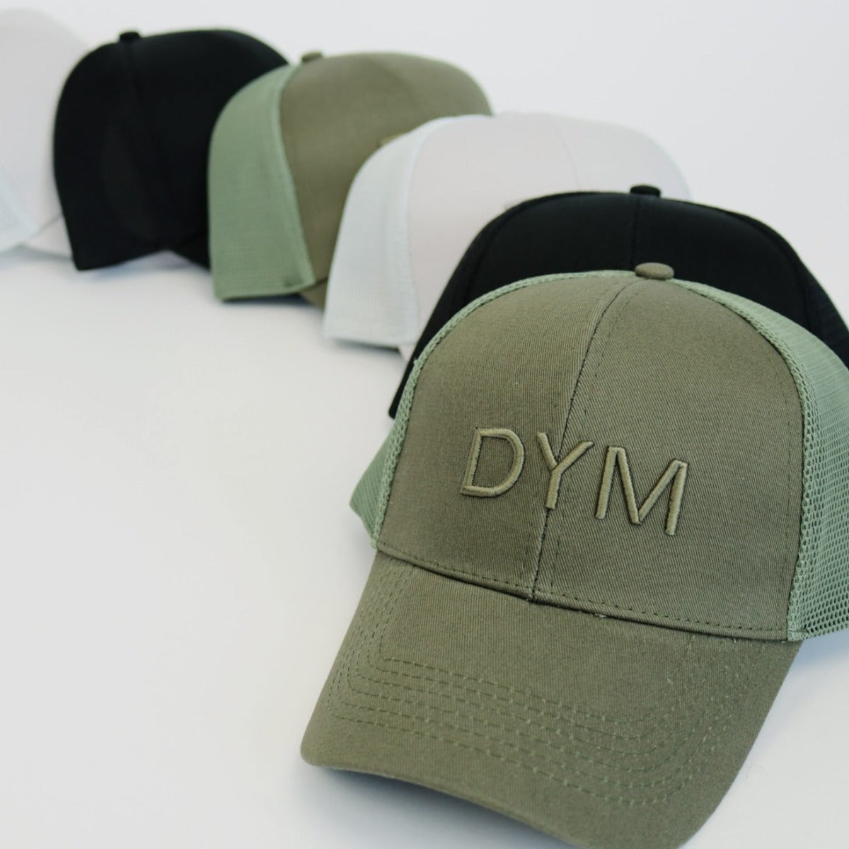 Close-up of DYM Athletics Trucker Hats in various colors, featuring the embroidered logo, arranged neatly on a white surface.