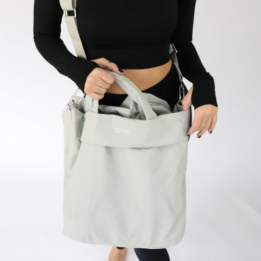 Stylish In Motion Bag by DYM Athletics held by a person, showcasing its practical design and lightweight fabric.