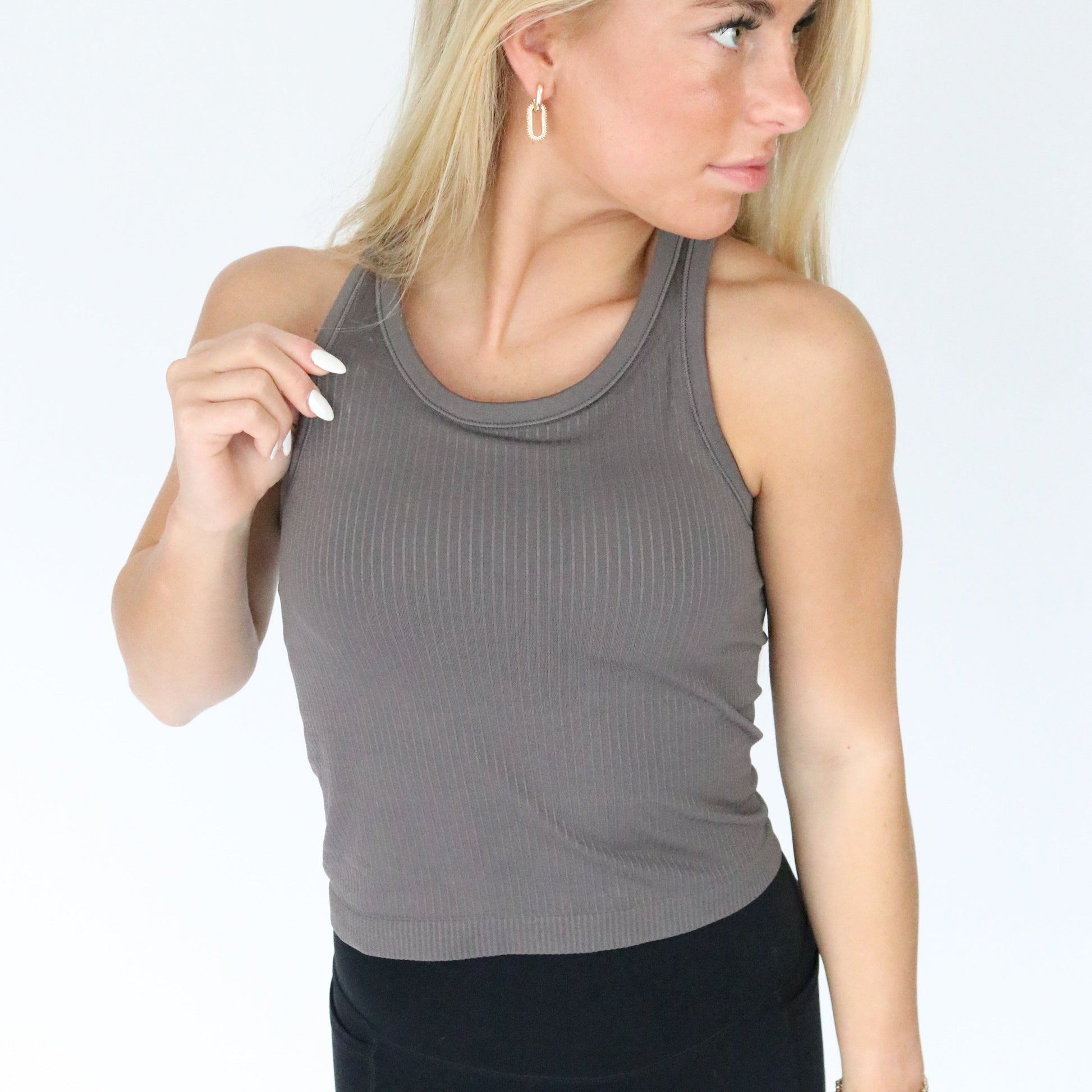Model wearing the Restore Ribbed Comfort Tank with Built-in Bra by DYM Athletics in a chic gray color, showcasing its stylish design and flattering fit.