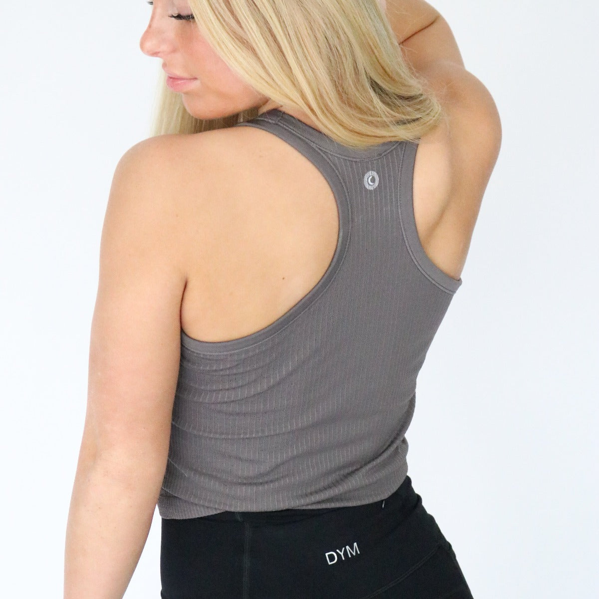 Back view of the model in the Restore Ribbed Comfort Tank with Built-in Bra by DYM Athletics, highlighting the tank's racerback style and supportive fit.