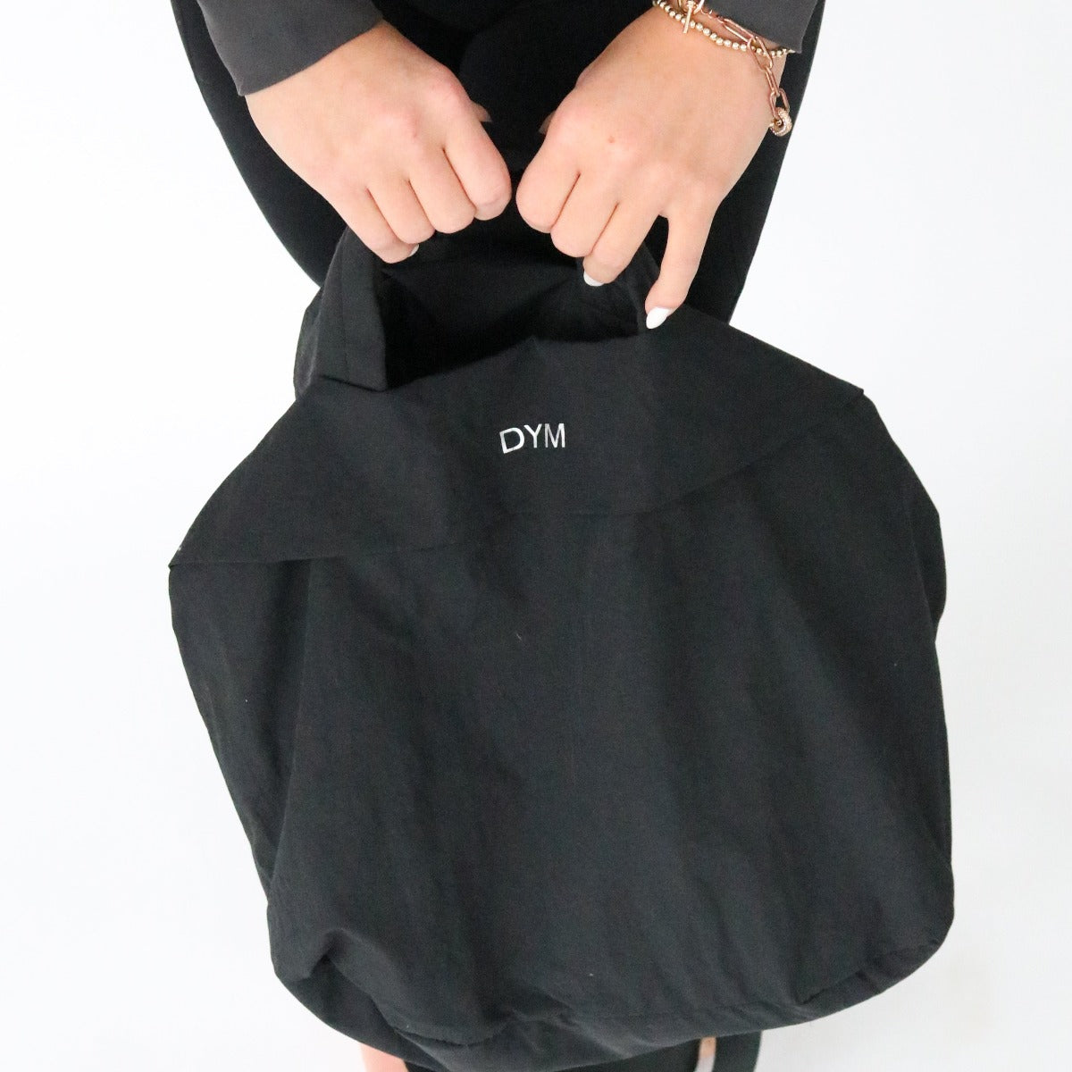 DYM Athletics In Motion Bag in black, held by a person showcasing its stylish design and practical features.