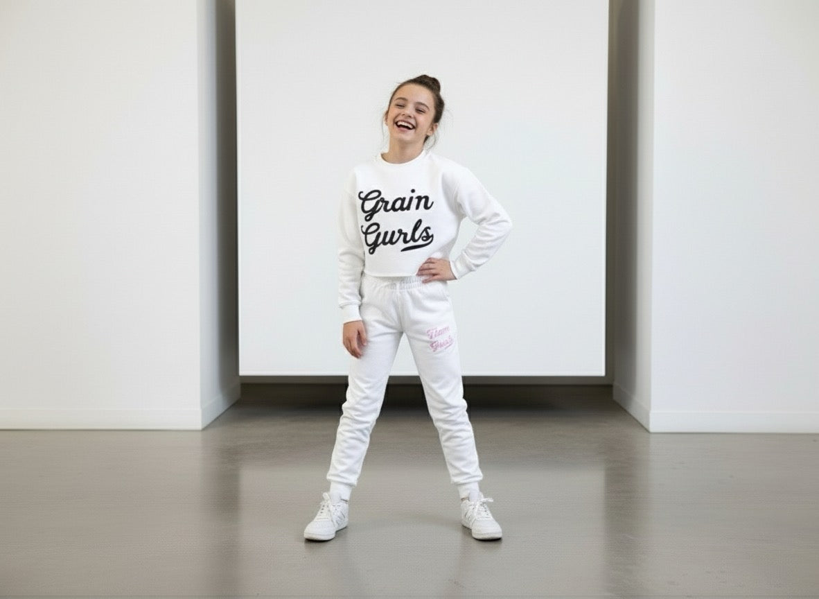 A cheerful girl posing in a Customized Glam Gurls Cropped Hoodie with Puff Print and matching joggers, exuding a stylish and comfy look in white, designed by Glam Gurls.