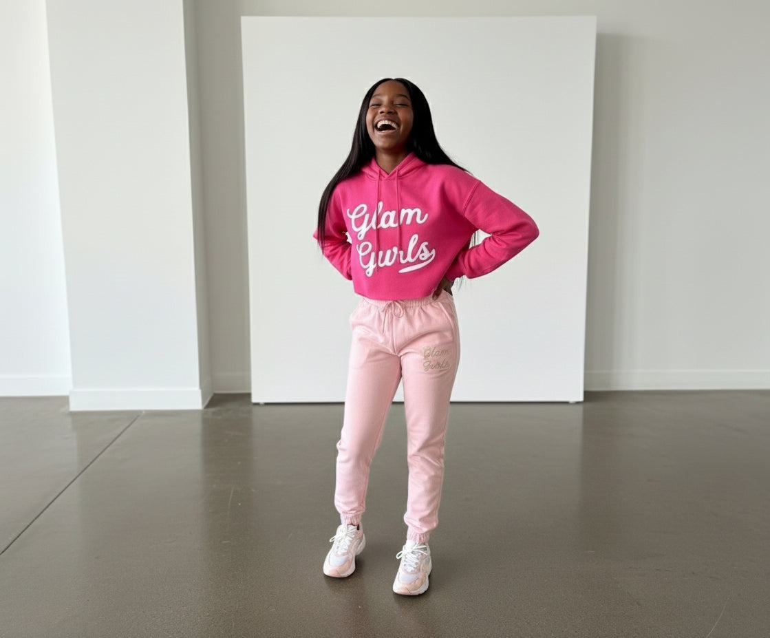 A joyful girl laughing while wearing a pink Customized Glam Gurls Cropped Hoodie with Puff Print, matchingly paired with pink joggers, highlighting the comfy and trendy design by Glam Gurls.