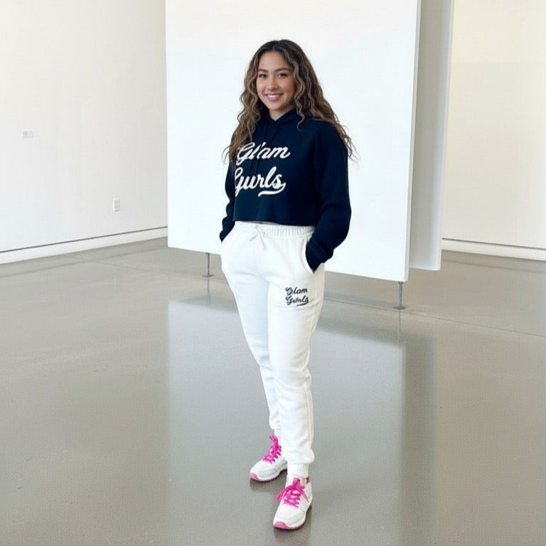 Model wearing Customized Glam Gurls Cropped Hoodie with Puff Print in a cozy setting, paired with white joggers, showcasing the stylish and comfortable vibe. Available in sizes S-XL from Glam Gurls.