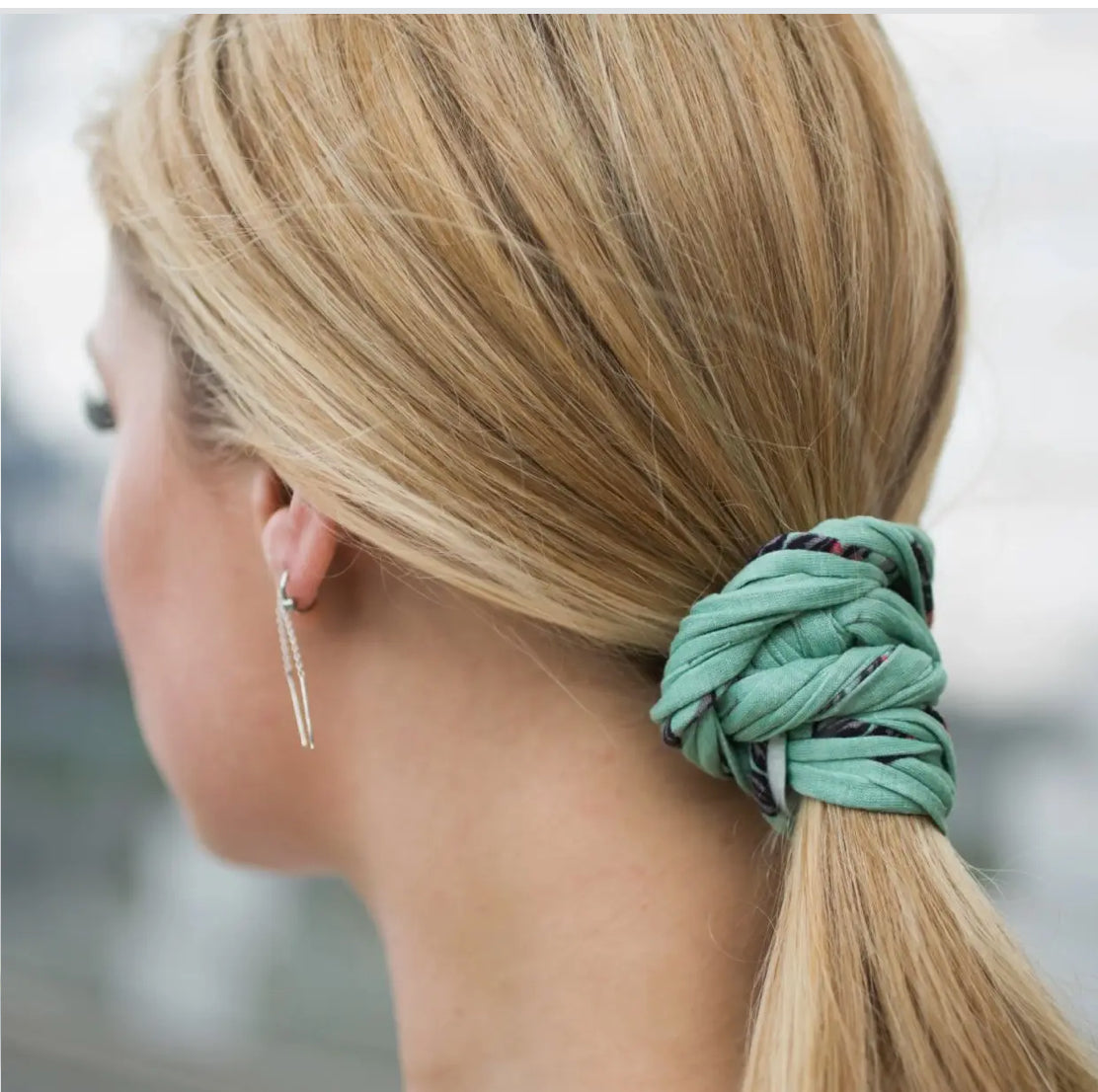 Close-up of a Bela Band Headband being used as a scrunchie, featuring a trendy green color and eco-friendly material from Bela Band.