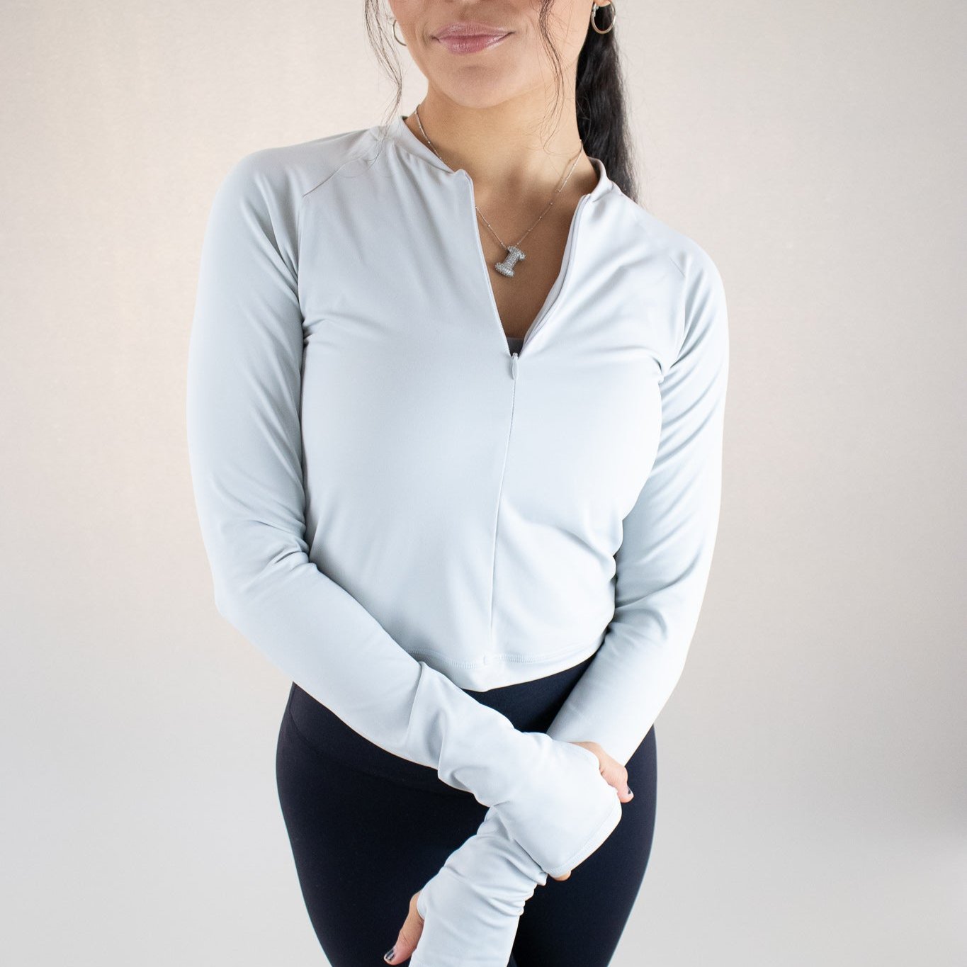 Smiling female model wearing the DYM Athletics Elite 1/4 Zip Long Sleeve, displaying a chic and athletic style.