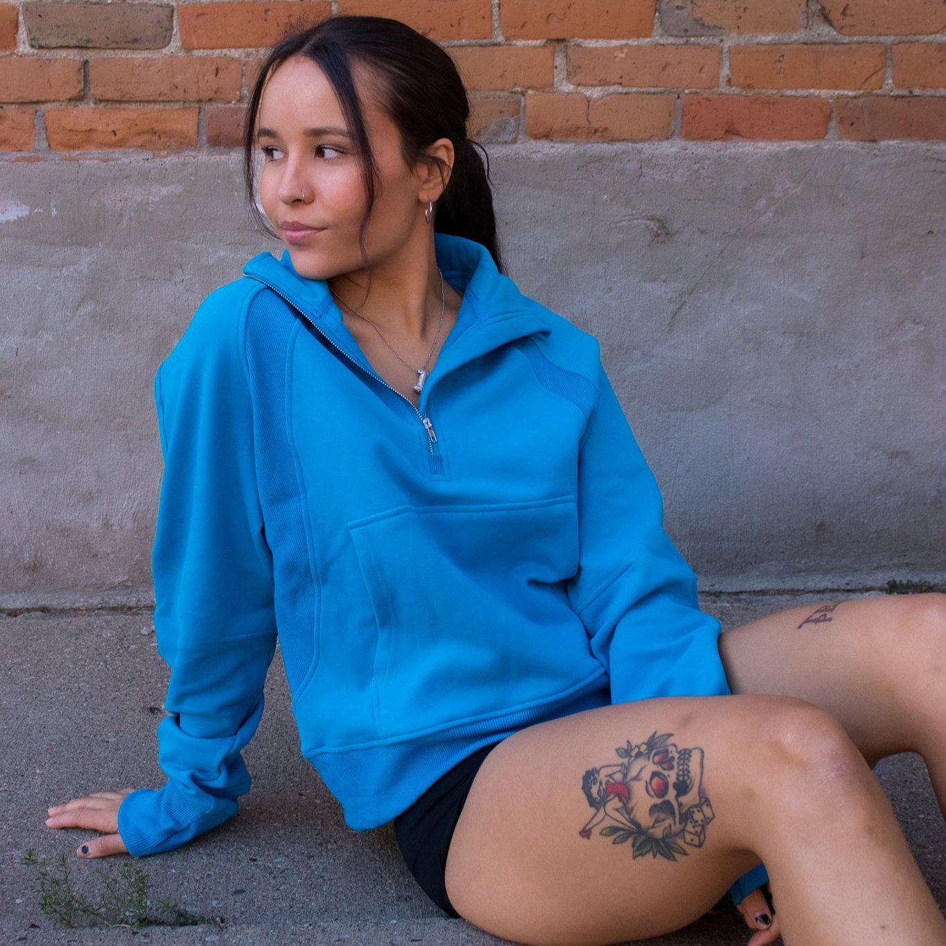 Cozy Up Full Length 1/2 Zip Sweatshirt by DYM Athletics, model sitting casually in a vibrant blue sweatshirt, showcasing its stylish design and comfortable fit.