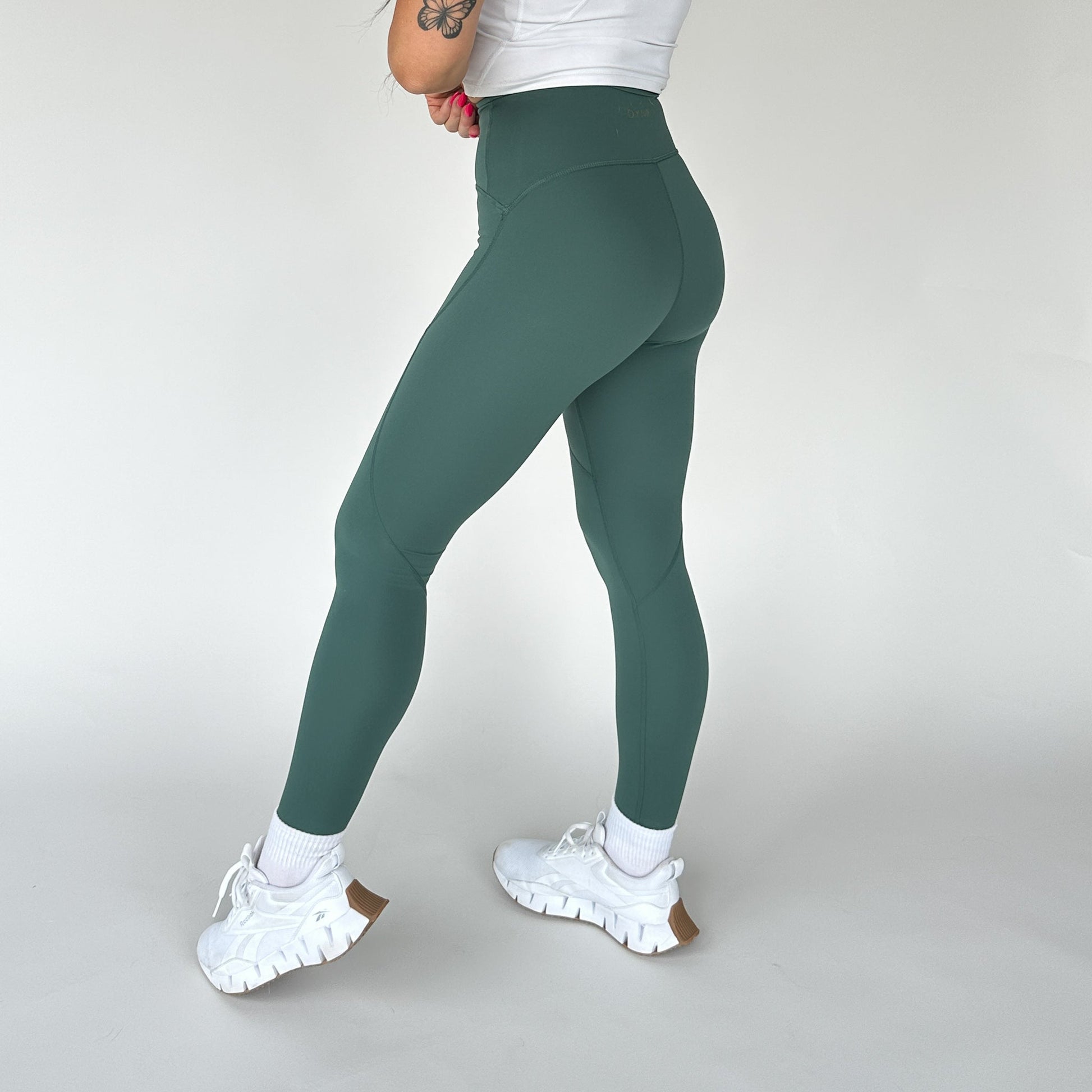 Side view of a model wearing DYM Athletics Trainer Muscle Tone Legging in green, showcasing the high-waist design and sculpted fit.