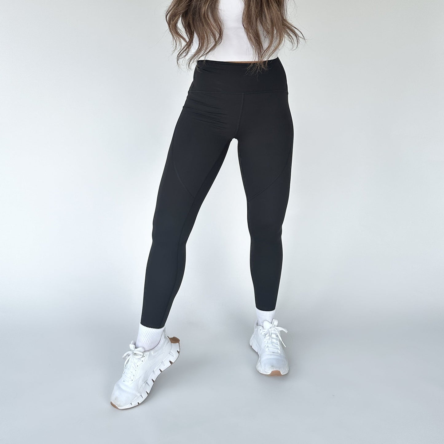 DYM Athletics Trainer Muscle Tone Legging showcased by a model standing in a stylish pose, wearing white sneakers and a fitted top, highlighting the high-waist design.