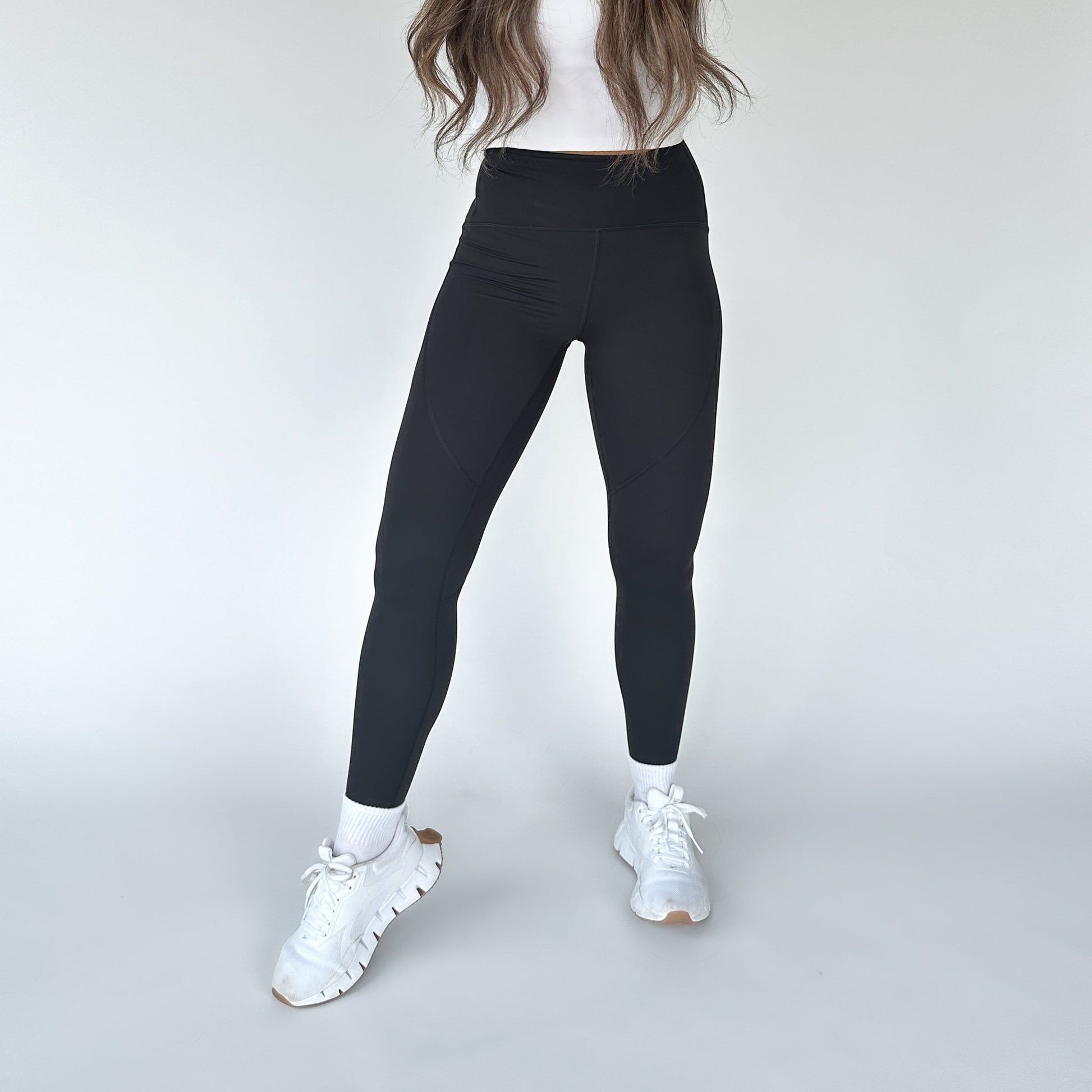 DYM Athletics Trainer Muscle Tone Legging showcased by a model standing in a stylish pose, wearing white sneakers and a fitted top, highlighting the high-waist design.