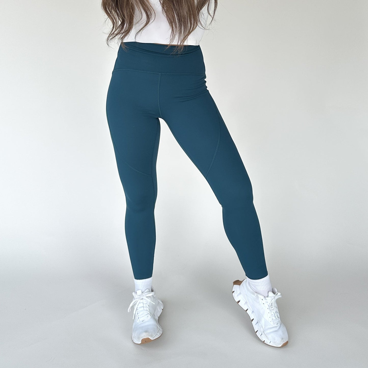 Front view of a model in DYM Athletics Trainer Muscle Tone Legging in teal, demonstrating the snug high-compression fit and stylish look.