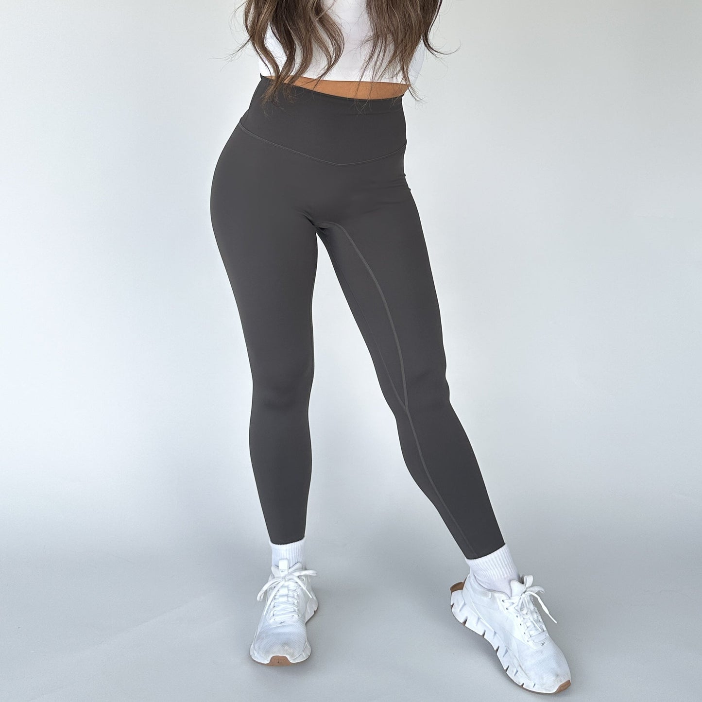 Model showcasing High Society Sculpting Legging from DYM Athletics in a dark gray color, combining functionality with style for any activity.