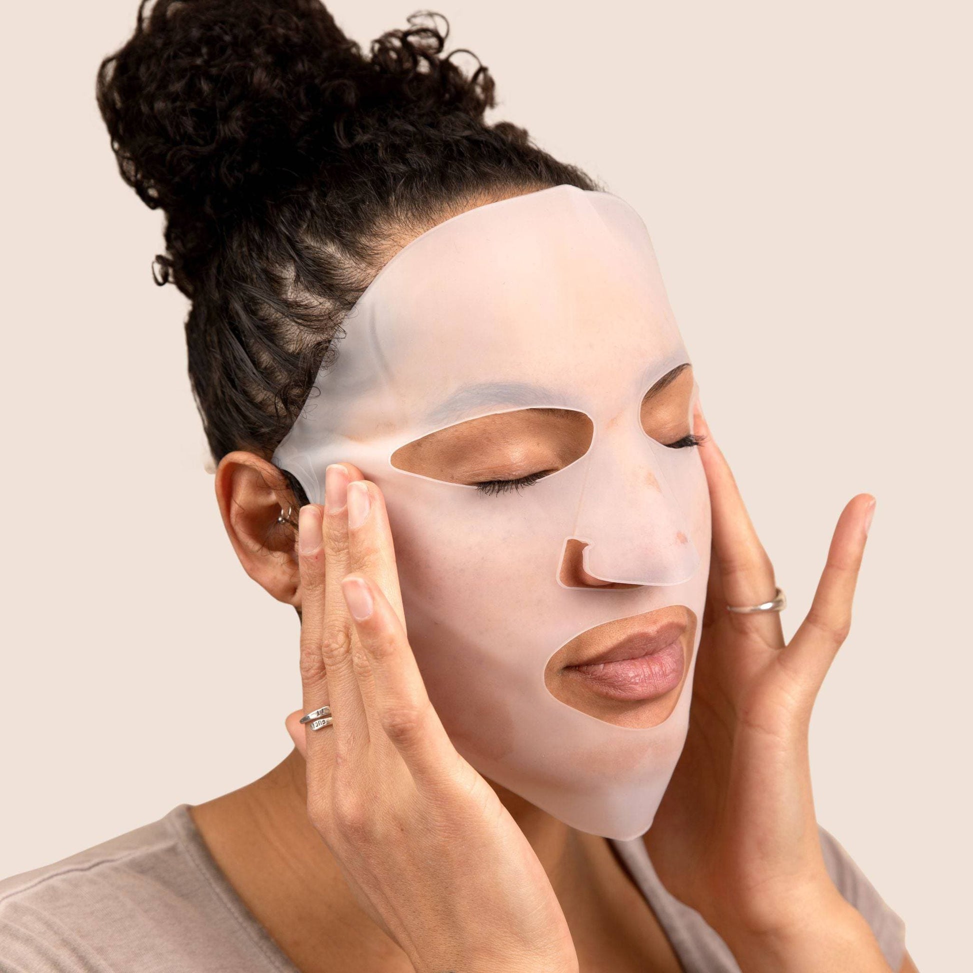 A person using the Reusable Silicone Hydro Mask by Cosmedica Skincare, applying it to their face for effective moisture retention.