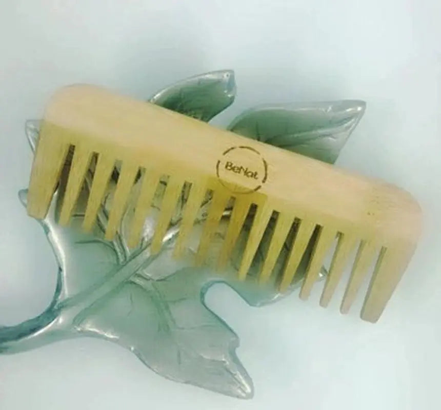 BeNat Eco-Friendly Bamboo Hair Comb resting on a leaf, showcasing its natural bamboo material and eco-friendly design.