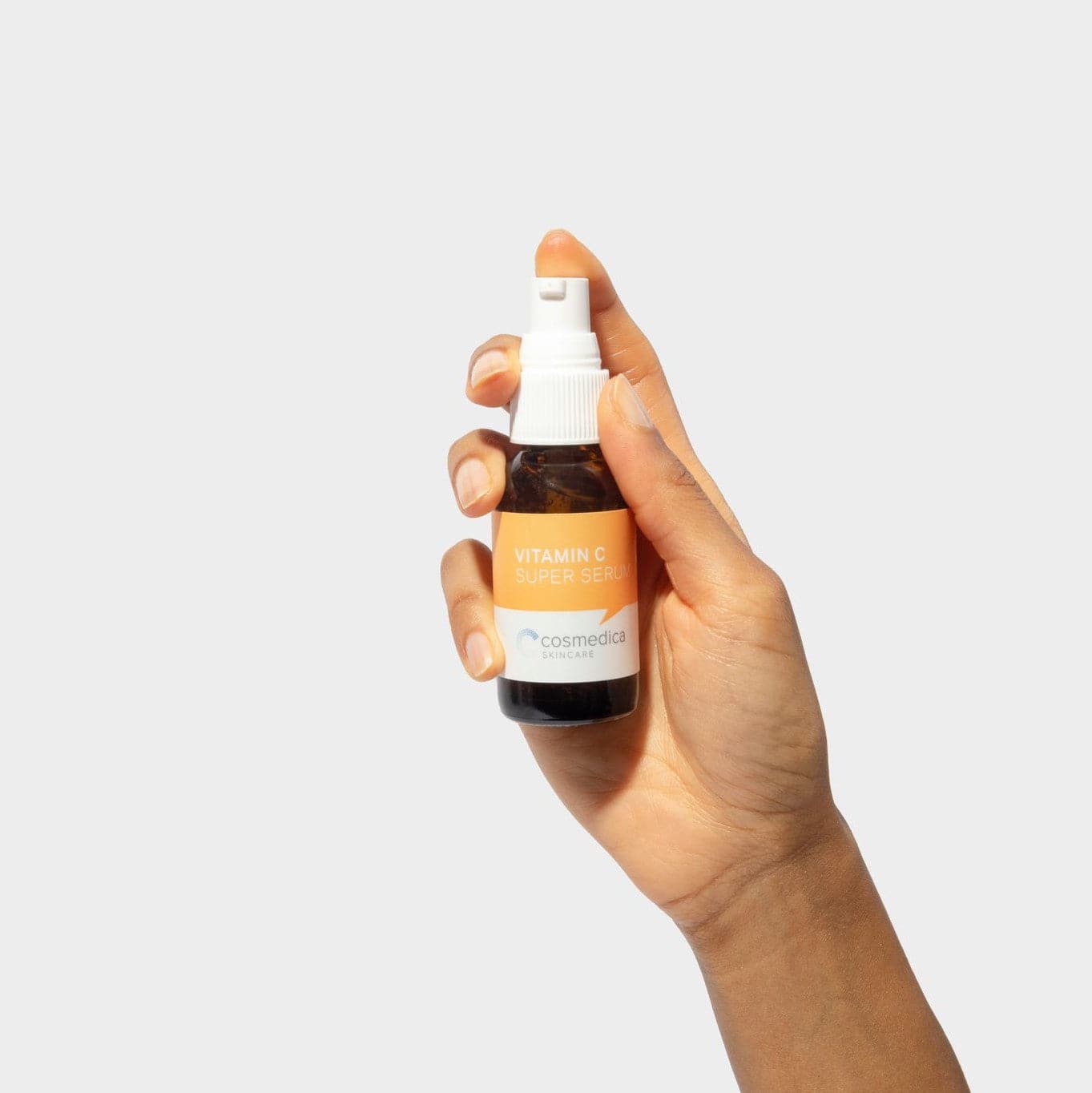 A hand holding Cosmedica Skincare Vitamin C Super Serum, showcasing the sleek bottle design and label for an effective anti-aging skincare solution.