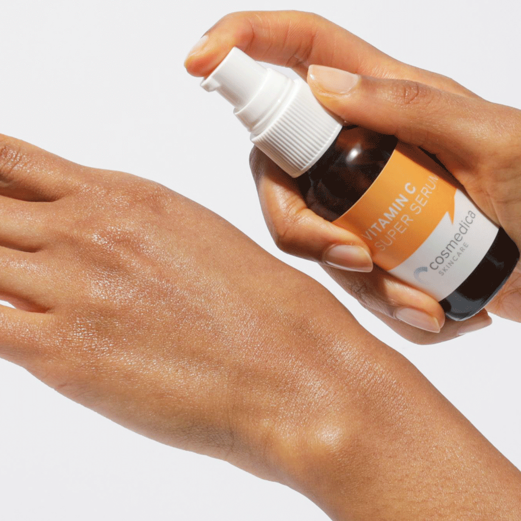 A hand applying the Vitamin C Super Serum from the Hyaluronic + Vitamin C Serum Set by Cosmedica Skincare, highlighting its brightening properties.