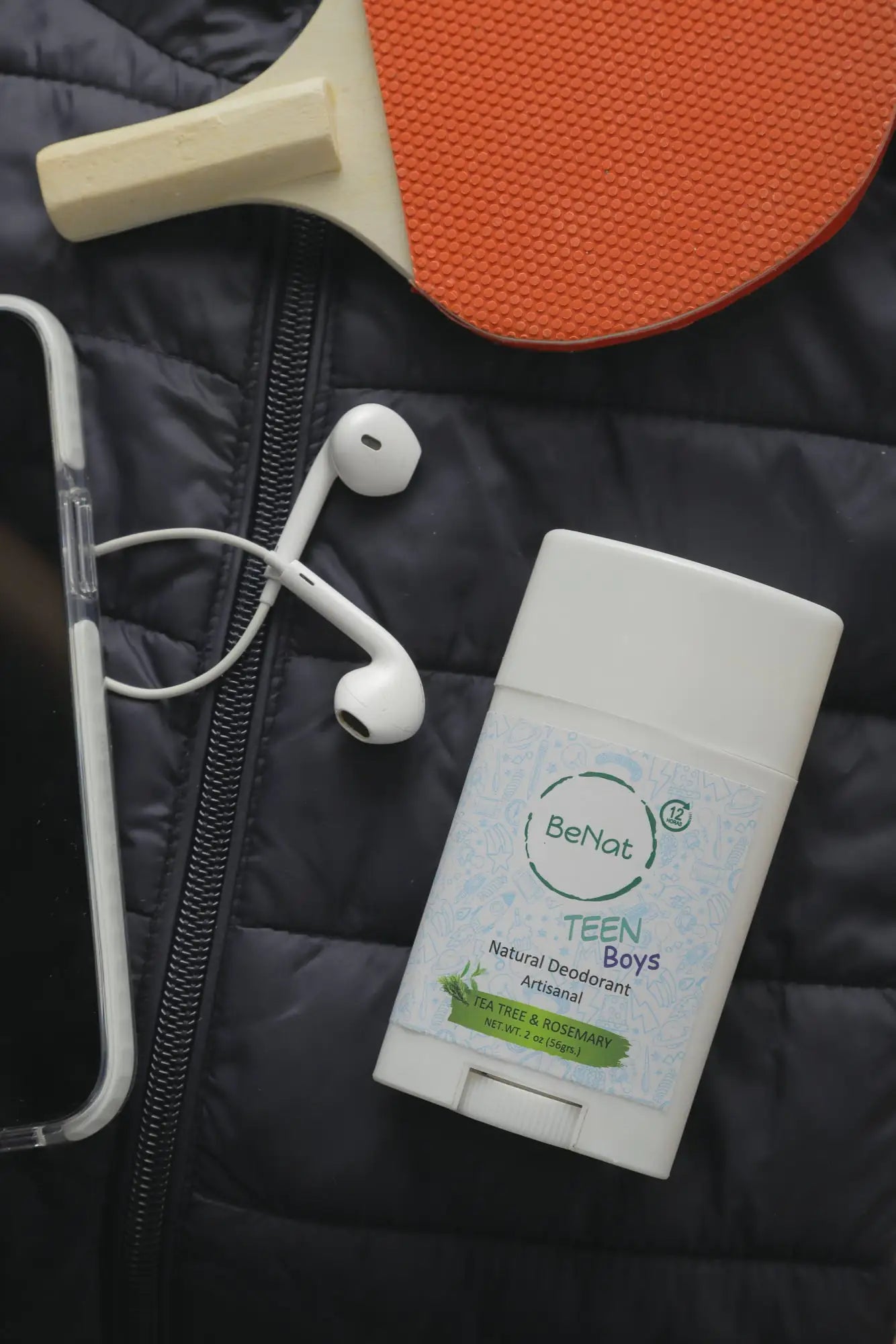 BeNat All-Natural Deodorant Stick for Teens Boys beside earbuds and a smartphone, showcasing its convenience for active lifestyles.